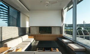 Modern minimalist living room with large windows, flat-screen TV, and white and gray furniture