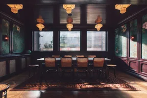 A sophisticated, modern restaurant interior with wooden tables, leather chairs, and glass window panels.