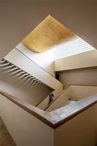 Modern staircase with wooden railings and concrete steps, featuring a skylight in the ceiling.