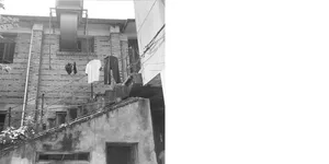 Black and white photograph of an old, urban residential building with clothes drying on the balcony.