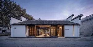 傳統店面採用木質外觀搭配玻璃展示窗，背景為白色瓷磚立面。