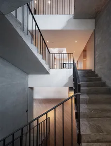 Modern concrete staircase with black metal railings and white walls.