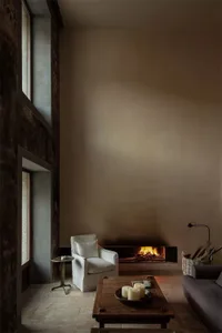 Minimalist living room featuring a stone, wood, and concrete design scheme with a fireplace, sofa, and coffee table.