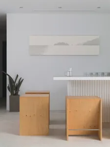 Minimalist design featuring wooden stools, a white counter, and a serene seascape painting.