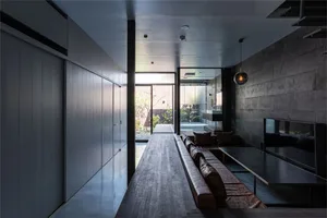 A minimalist living room with concrete, leather, and metal finishes.