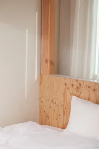 White bed with wooden paneling in a minimalist bedroom setting.
