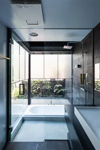 Modern minimalist bathroom with concrete walls and floor, featuring a serene garden view through large windows.