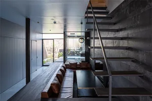 Modern living room with concrete walls and a concrete staircase leading to another level.