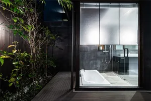 A modern minimalist bathroom with concrete walls and a glass door shower.