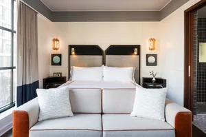 Modern, minimalist bedroom with white bedding and bedside tables.