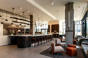 A modern industrial lobby with concrete walls and floors, featuring sleek seating and a bar area.