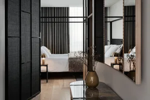 A minimalist bedroom featuring fabric bedding, a wooden floor, and metallic accents.