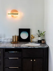 A modern bar with a marble countertop featuring a sink, faucet, and decorative items.