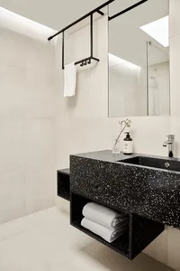 A modern black concrete bathroom with a floating vanity, white towels, and a glass mirror.