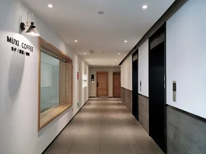 Modern coffee shop hallway with gray tiles, wooden doors, and industrial lighting