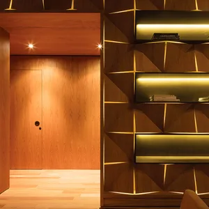 A modern library with a wooden shelf featuring geometric design and built-in lighting.