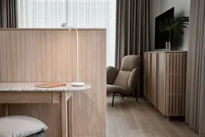 Modern living room featuring a wooden floor and furniture, along with a comfortable seating area and a table lamp.