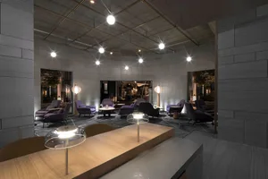 A modern lobby area with concrete walls, wooden tables, and purple armchairs.