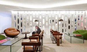 A modern lobby interior featuring concrete, glass, and wooden furniture and seating arrangements.