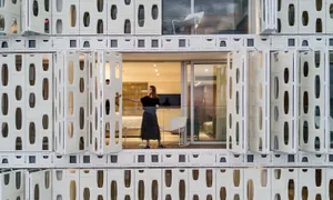 A modern residential interior design featuring glass walls and a woman standing on a balcony.