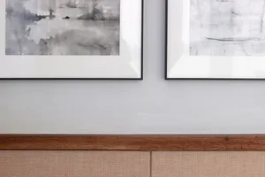 A framed abstract watercolor painting mounted on a wall with a wooden ledge below.