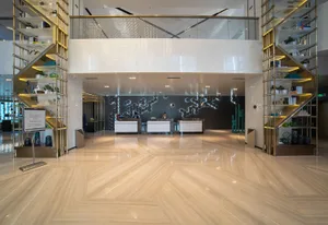 A spacious hotel lobby featuring metallic glass and marble reception counters, illuminated by modern lighting and sleek furni