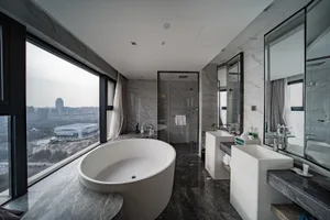 Modern bathroom featuring a freestanding bathtub with a cityscape view through large windows and marble flooring.