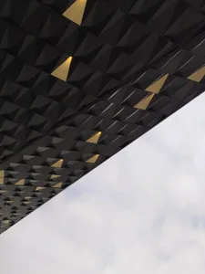 A modern ceiling with a metallic black texture and geometric patterns featuring yellow accents.