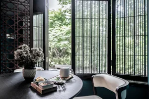 A cozy coffee shop with a wooden table, white chairs, and a vase of flowers.