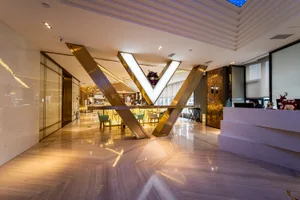 Modern hotel reception area with marble flooring, glass walls, and metal accents.
