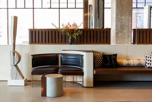 A modern office space featuring a wooden desk and seating area with black cushions.