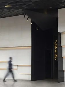 A modern lobby featuring a black textured wall and illuminated lighting fixtures.