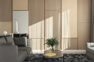A modern minimalist living room featuring wood paneling, a round coffee table with flowers and a book, and gray sofas.