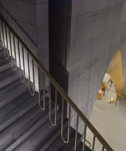A modern staircase with metallic railings and dark tiles.