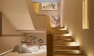 Modern staircase with wooden steps and railings, illuminated by soft lighting, featuring a minimalist design aesthetic.