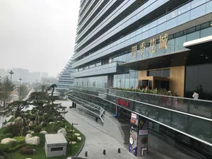 A modern urban building with glass and concrete facade, featuring a landscaped exterior walkway.