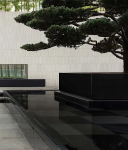 Contemporary landscape design featuring concrete planters and metal structures with a tree and greenery.