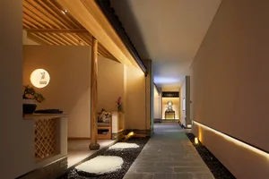 Stone pathway with wood beams and glass walls in a modern interior corridor.