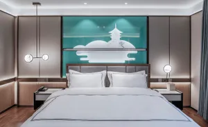 Modern minimalist bedroom with light wooden flooring, white bedding, and a neon light artwork above the bed.