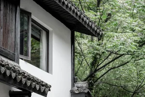 傳統房屋屋頂覆蓋陶土瓦片，水泥牆面，四周環繞綠意。