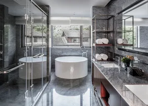 A modern bathroom interior featuring a marble and concrete design with a circular bathtub and minimalist fixtures.
