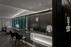 A modern lobby featuring a black metal counter and seating area with a branded logo on the wall.