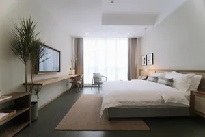 A modern minimalist bedroom with white walls, furniture, and decor.