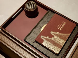 Three books and a small decorative object on a wooden tray