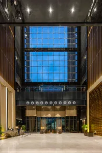 Modern hotel lobby featuring a glass atrium and marble flooring.