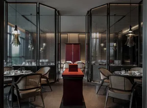 A sleek, minimalist restaurant interior featuring metallic tables and chairs.