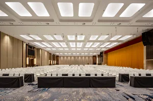 A spacious conference center with hardwood floors and rows of white chairs.
