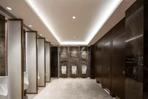 A modern, industrial public bathroom interior with marble walls and wooden partitions.