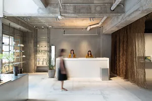 A reception desk with industrial design elements, featuring exposed concrete walls and a simple, minimalist aesthetic.