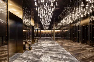 A luxurious hotel lobby featuring marble flooring, hanging chandeliers, and modern lighting fixtures.